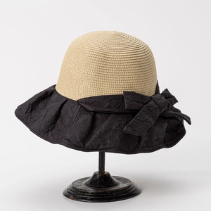 Close-up of pleated black brim and large bow detail on a straw sun hat for women