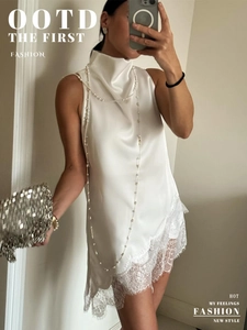 Detailed close-up of white satin sleeveless top featuring elegant lace trim hem and high neck