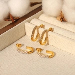 U-shaped gold earrings with embedded pearls and diamonds on a vintage jewelry box