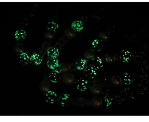 Détail macro de perles de sable vert brillant avec effet lumineux sur un collier