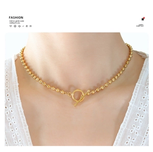 Detailed view of women's gold ball chain necklace with OT toggle clasp and lace detail
