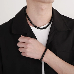 Détail de la parure chaîne gourmette noir mat montrant la texture sur le modèle masculin