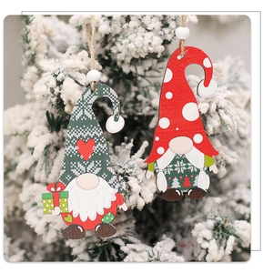 Close-up of wooden gnome ornaments in red and green hanging on a snowy Christmas tree