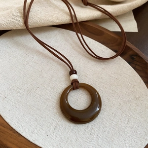 Gros plan détaillé du pendentif géométrique en résine brune sur plateau en bois et toile