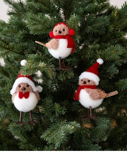 Detailed view of three plush Christmas bird ornaments hanging on a green festive tree