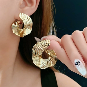 Detailed view of textured gold spiral earrings with elegant striped shell-like metal design
