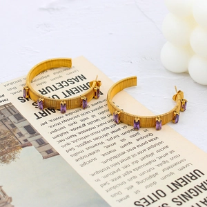 Macro shot of gold hoop earrings with wire wrap texture and rectangular purple zircons