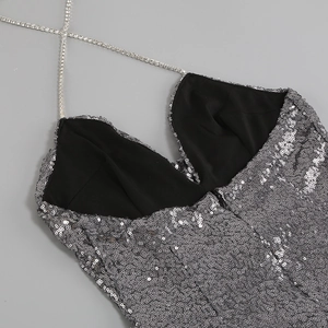 Détail d'une robe à paillettes argentées avec bretelles croisées en strass et col en V