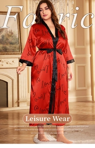 Detail of red satin robe with black lace trim and love pattern in a cozy indoor setting