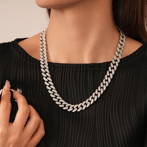 Close-up of a silver-toned Cuban link chain necklace with pavé-set crystals on a model