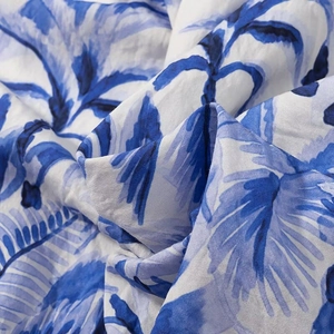 Close-up of tropical leaf print fabric showing blue and white textile texture and material