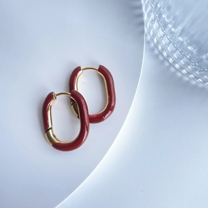 Detailed top view of retro U-shaped gold earrings with dark red enamel on white plate
