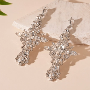 Close-up of vintage teardrop cross earrings with sparkling rhinestones on white rock