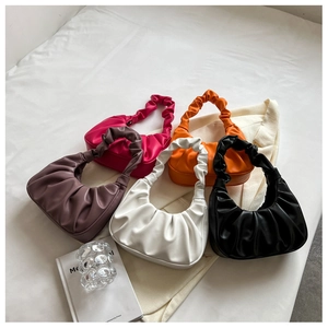 Chic ruched underarm bags displayed in five vibrant colors on a minimalist bed setting