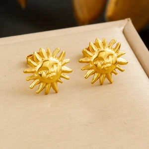 Detail view of gold-plated sun face earrings with embossed texture and metal finish