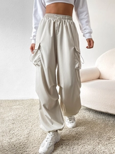 Detail of high waist beige cargo pants with drawstring waist and large flap pockets
