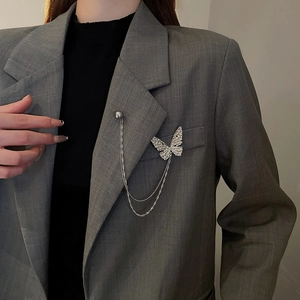 Detailed view of a silver butterfly chain brooch with grey pearl on grey suit lapel