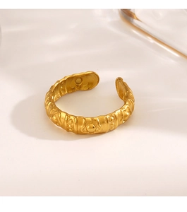 Close-up of golden adjustable ring featuring vintage embossed flower patterns and dots