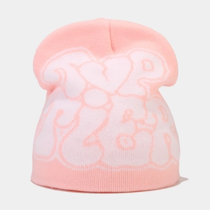 Close-up of pink and white knitted beanie featuring graffiti letter jacquard pattern