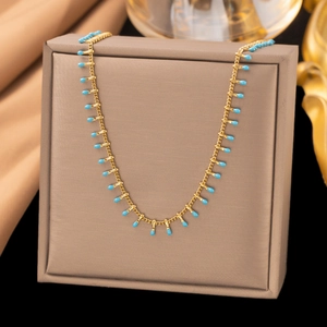 Collier élégant en or avec pendentifs gouttes bleu ciel sur support à bijoux en velours
