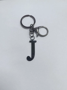 Detail of a black metal J-letter keychain with lobster clasp and round key ring