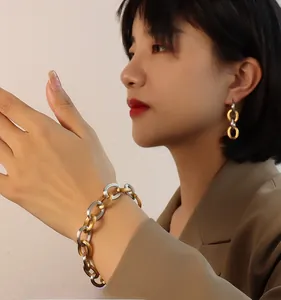 Detail shot of woman wearing 18K gold plated chain earrings and bracelet jewelry set
