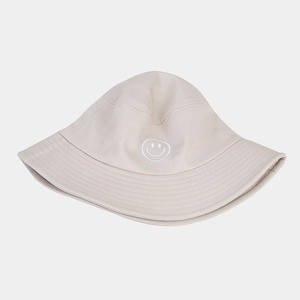 Détail d'un chapeau bob beige en coton avec un motif de smiley blanc brodé dessus
