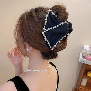 Détail d'une pince à cheveux élégante en tissu noir avec perles pour un chignon français
