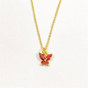 Gros plan détaillé du pendentif papillon doré avec zircons rouges et oranges