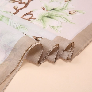 Detail of elegant silk scarf with green magnolia print and fine stitched rolled hem