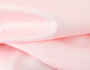 Macro detail of soft pink silk satin fabric with elegant drape and glossy texture
