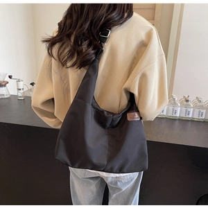 Detailed side view of black large capacity tote bag with leather tag and wide strap