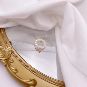 Close-up of French vintage freshwater pearl ring with gold letter J charm on silk