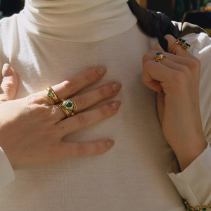 Close-up of vintage 18K gold stainless steel layered rings with green malachite stones