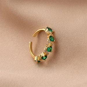 Macro shot of gold-plated adjustable ring with green zircon stones on silk fabric