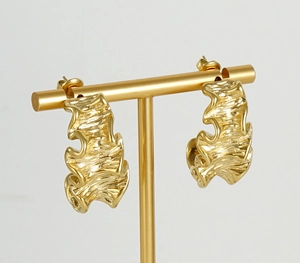 Macro view of gold titanium steel hoop earrings with unique irregular wavy texture detail