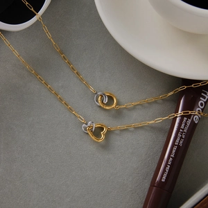 Detail of two-tone gold and silver heart and double ring necklaces with lifestyle props