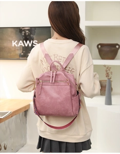 Rear view of pink PU leather backpack with colorful woven strap and double zippers
