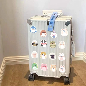 Detail of off-white hard shell suitcase with cartoon animal stickers and blue ribbon