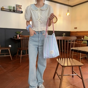 Photo lifestyle d'un grand sac en toile à rayures violettes et vertes dans un café cosy
