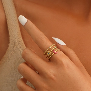 Close-up of gold beaded stackable rings with sun, moon, and star charms on model's hand