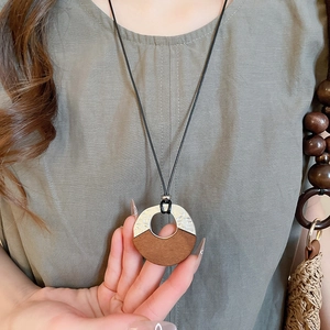 Detail of bohemian wooden and silver metal round pendant on black cord necklace