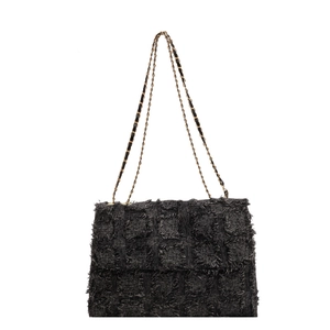 Black tweed tote bag with gold chain strap and fringe details on a white background