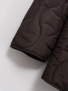 Detail of dark brown quilted jacket featuring elastic cuffs and smooth polyester texture