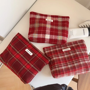 Détail de trousses à maquillage en laine à carreaux rouges avec étiquettes blanches