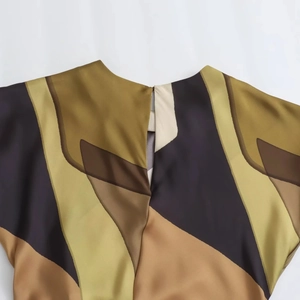 Detail of silk-satin dress showing keyhole neckline and geometric earth-tone prints