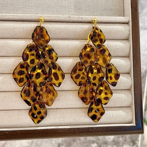 Detailed view of leopard print acrylic tassel earrings on a beige velvet jewelry box