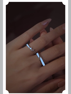 Macro close-up of luminous star ring glowing blue on hand in dark environment