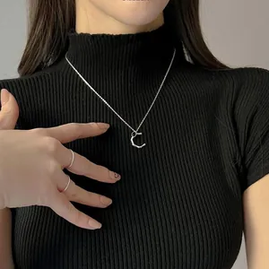 Dettaglio della collana in argento 925 con ciondolo a C e perla nera indossata