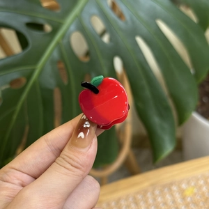 Cute red apple acetate hair claw clip for women in a lifestyle hand-held product shot